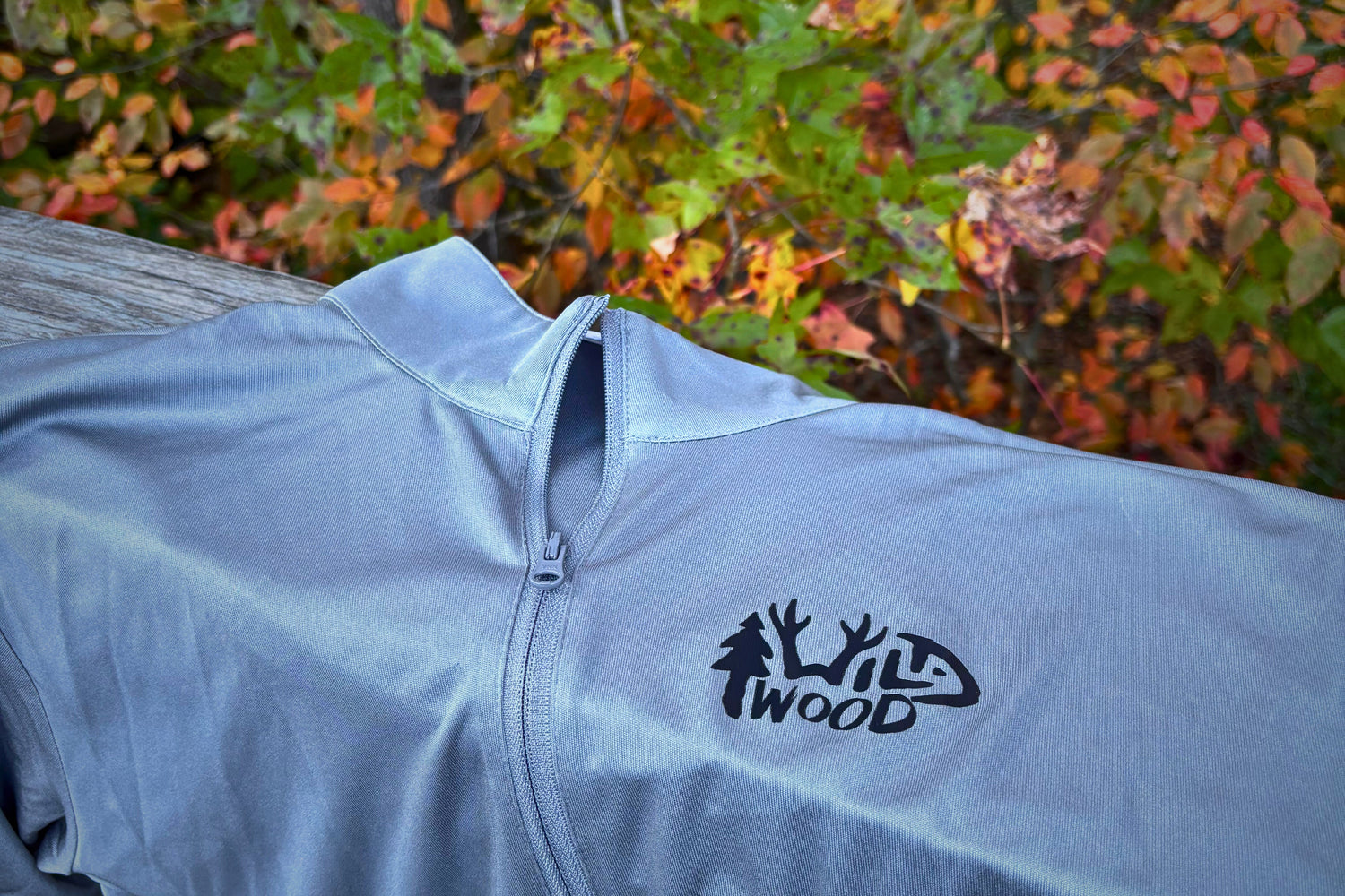 Light gray pullover on a bridge basking in the orange and green foliage.